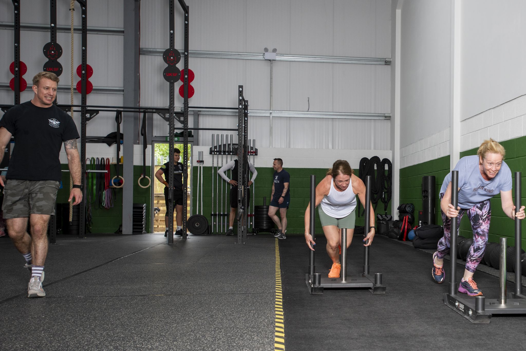Members pushing sleds in a CR Fitness session while a coach looks on