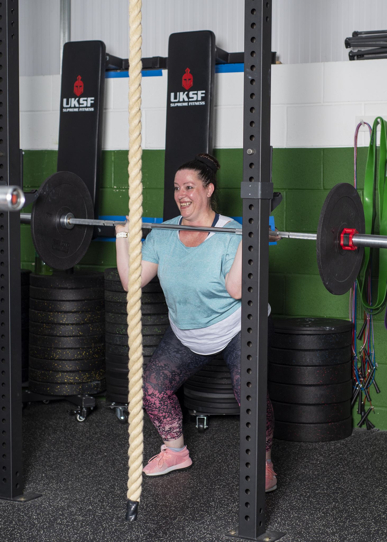 A CR Fitness member smiling mid-squat under a barbell
